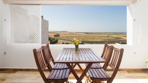 A wooden table and chairs on a balcony with a view of a landscape.