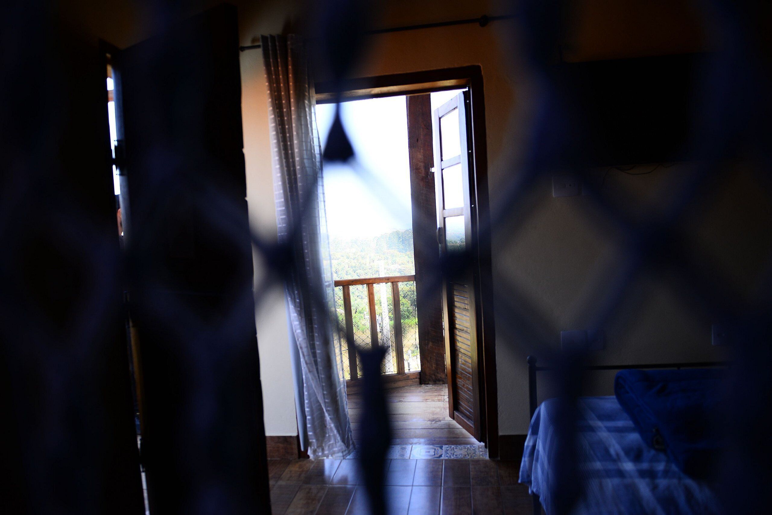 Ein Zimmer mit einem Bett, einer Holztür, die zu einem Außenbereich führt, und Blick ins Freie.