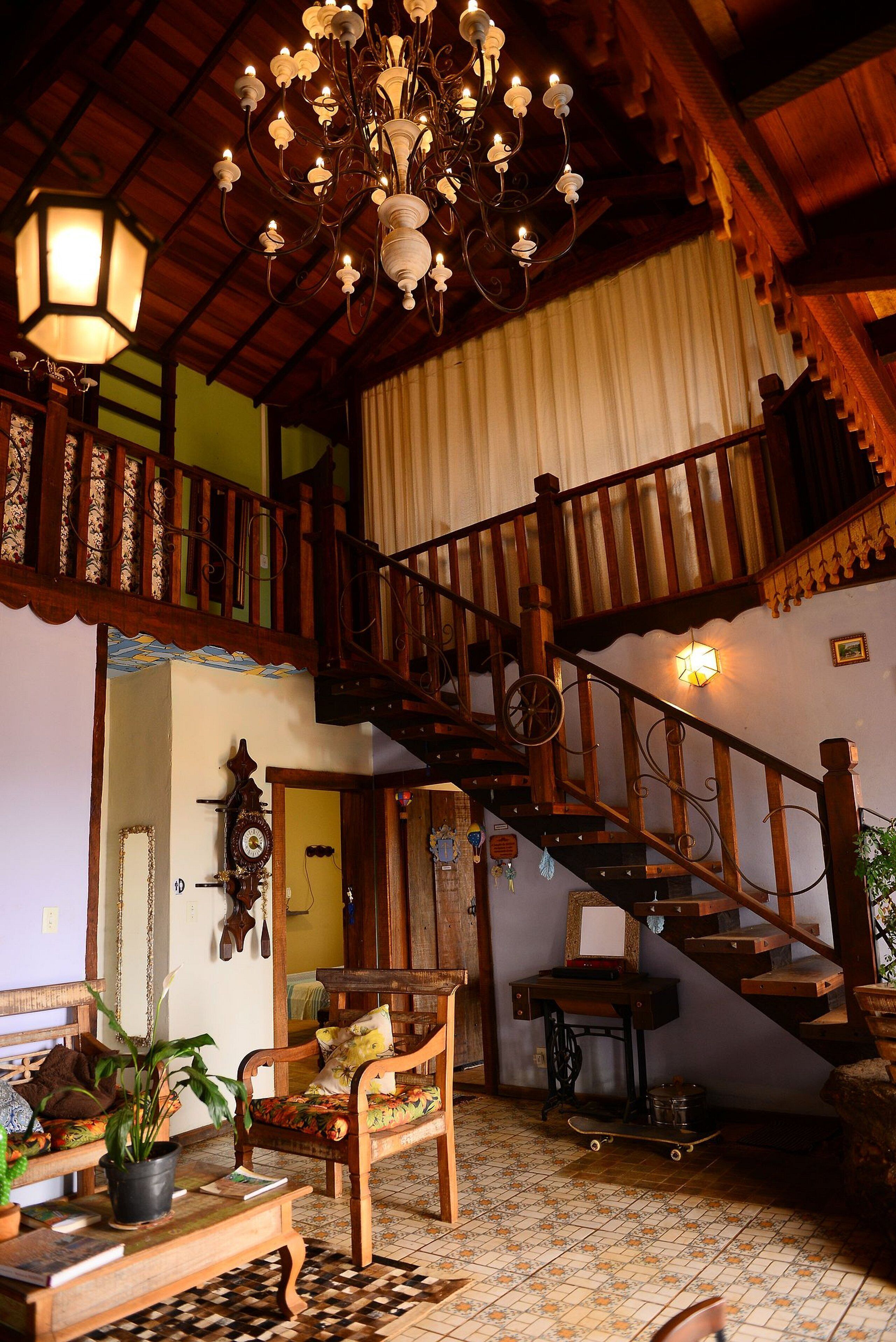 A traditional interior with a wooden staircase, a chandelier, and a patterned floor.