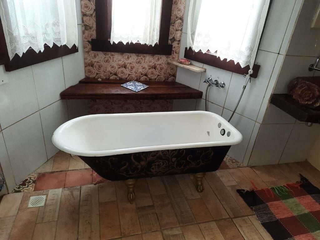 Een badkamer met een vrijstaand bad, een houten wastafelmeubel en een behang met een patroon.
