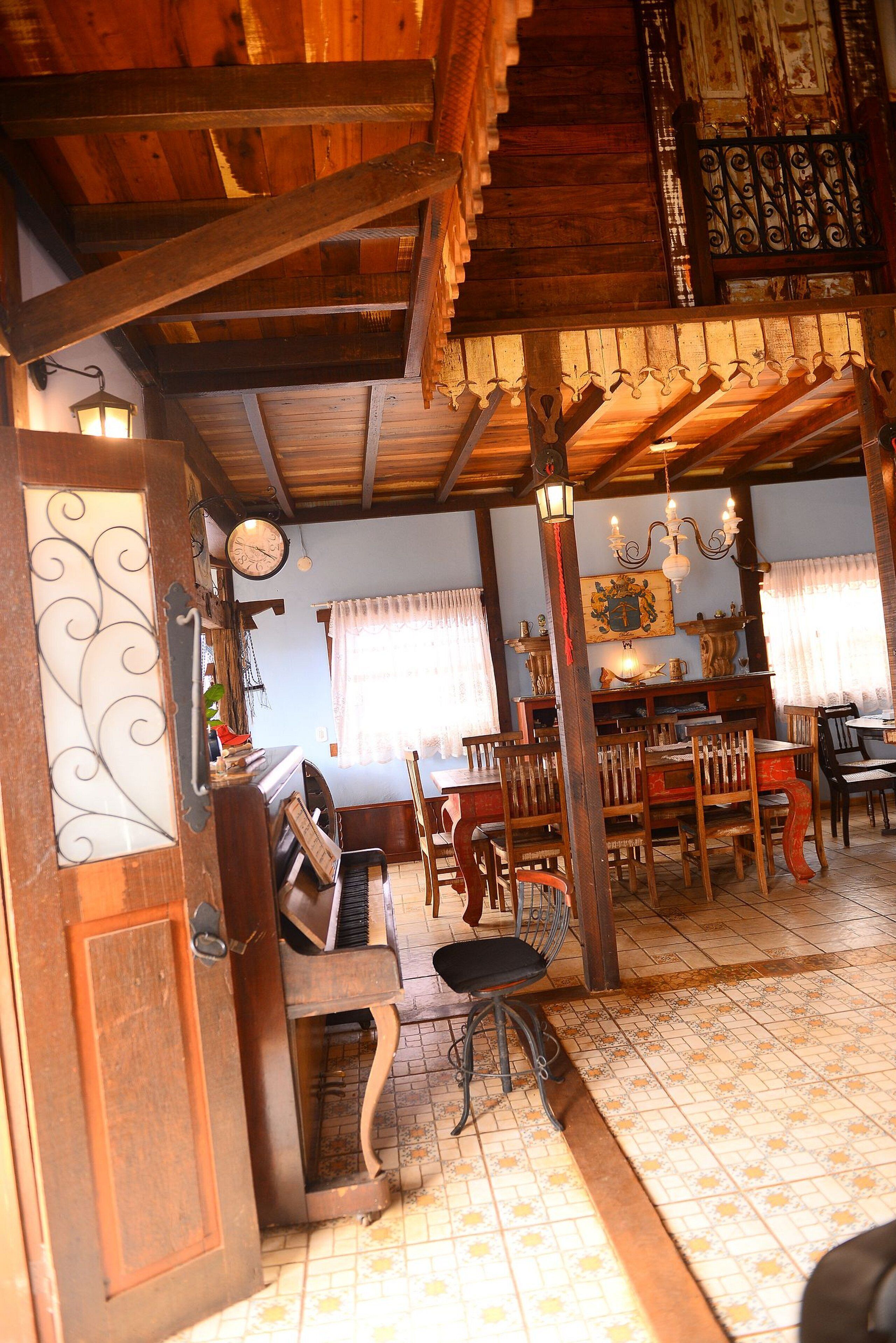 A wooden interior with a piano, chairs, and a dining table.