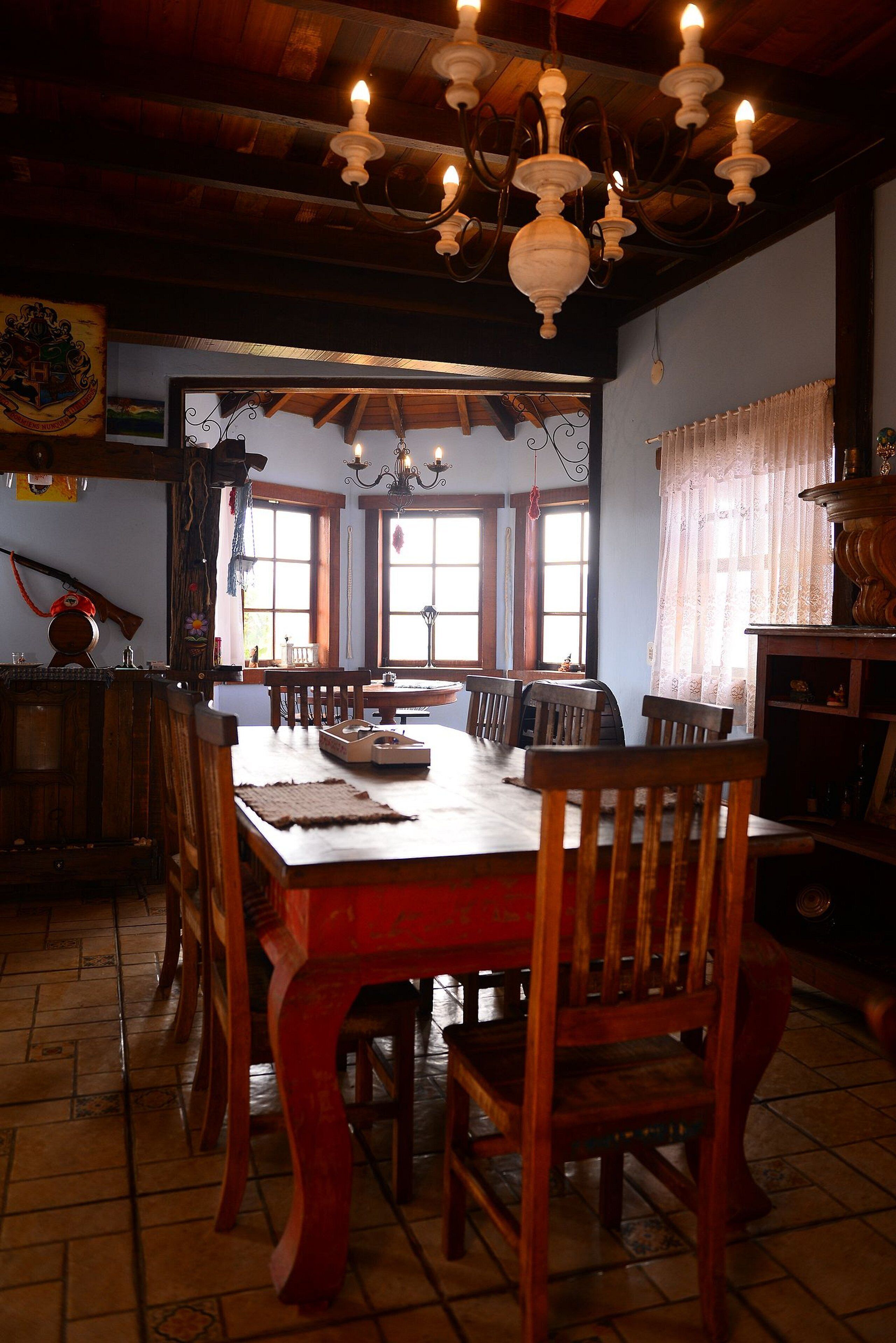 Un comedor tradicional con muebles de madera, un candelabro y ventanas grandes.