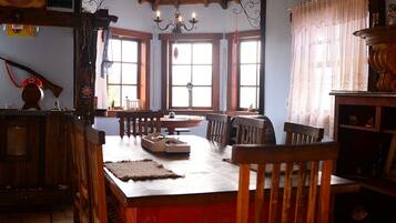 Un comedor tradicional con muebles de madera, un candelabro y ventanas grandes.