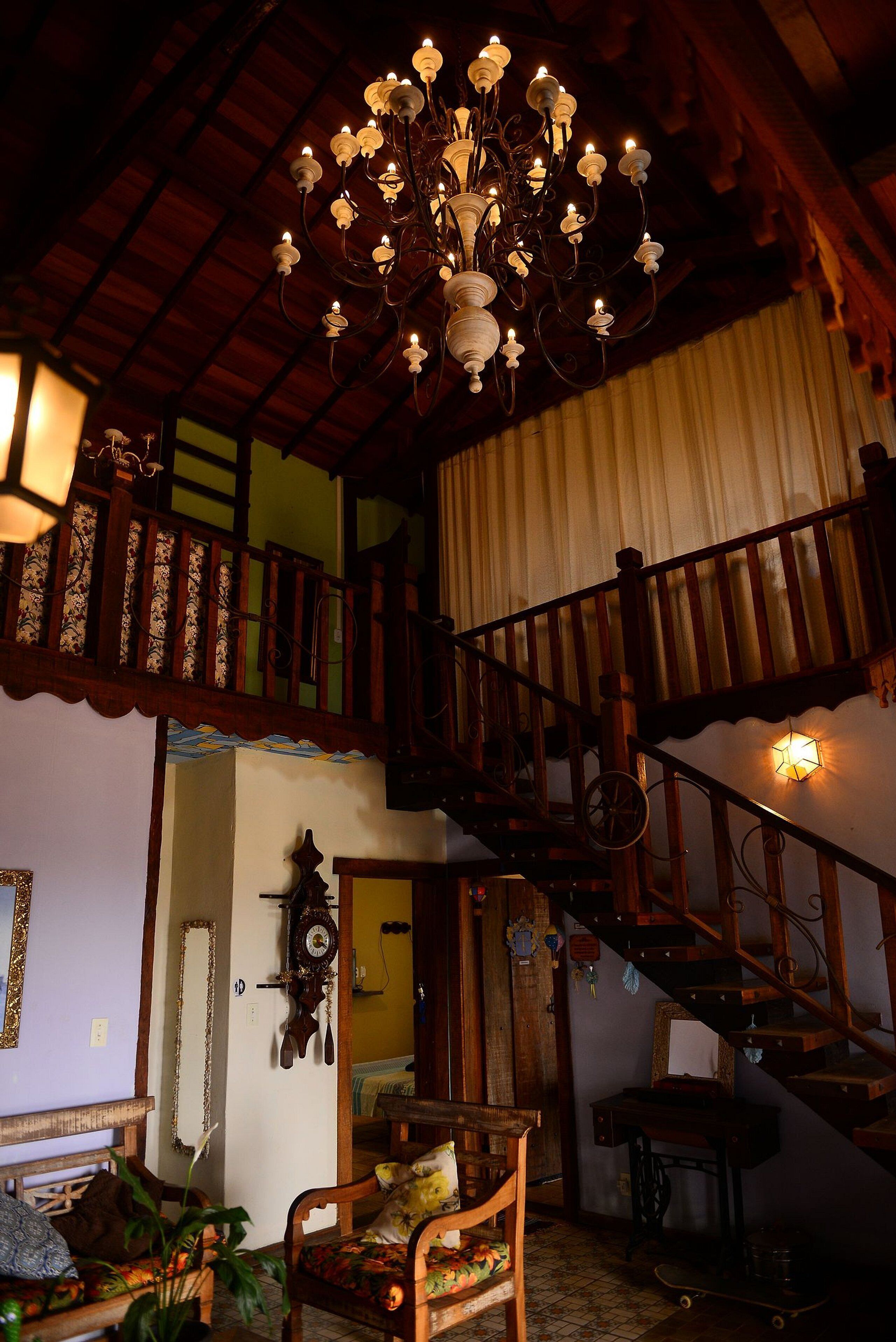 Una habitación amplia con una escalera de madera, un candelabro y un reloj en la pared.