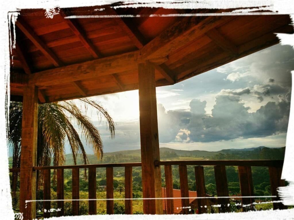 A wooden balcony with a view of a lush landscape and palm trees.