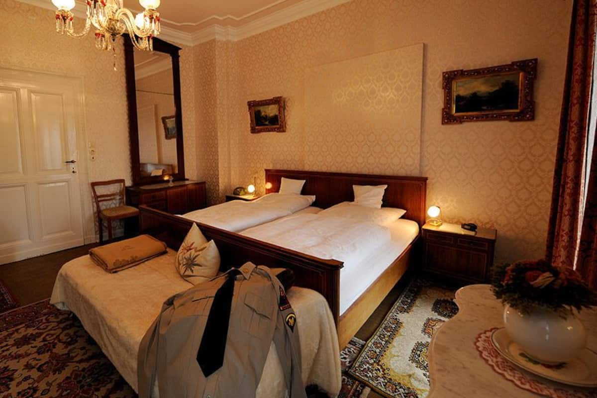 A hotel room with a double bed, a chair, a desk, and a mirror.