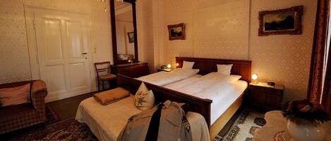 A hotel room with a double bed, a chair, a desk, and a mirror.