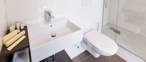 Un baño moderno con lavamanos, inodoro y cabina de ducha de vidrio.