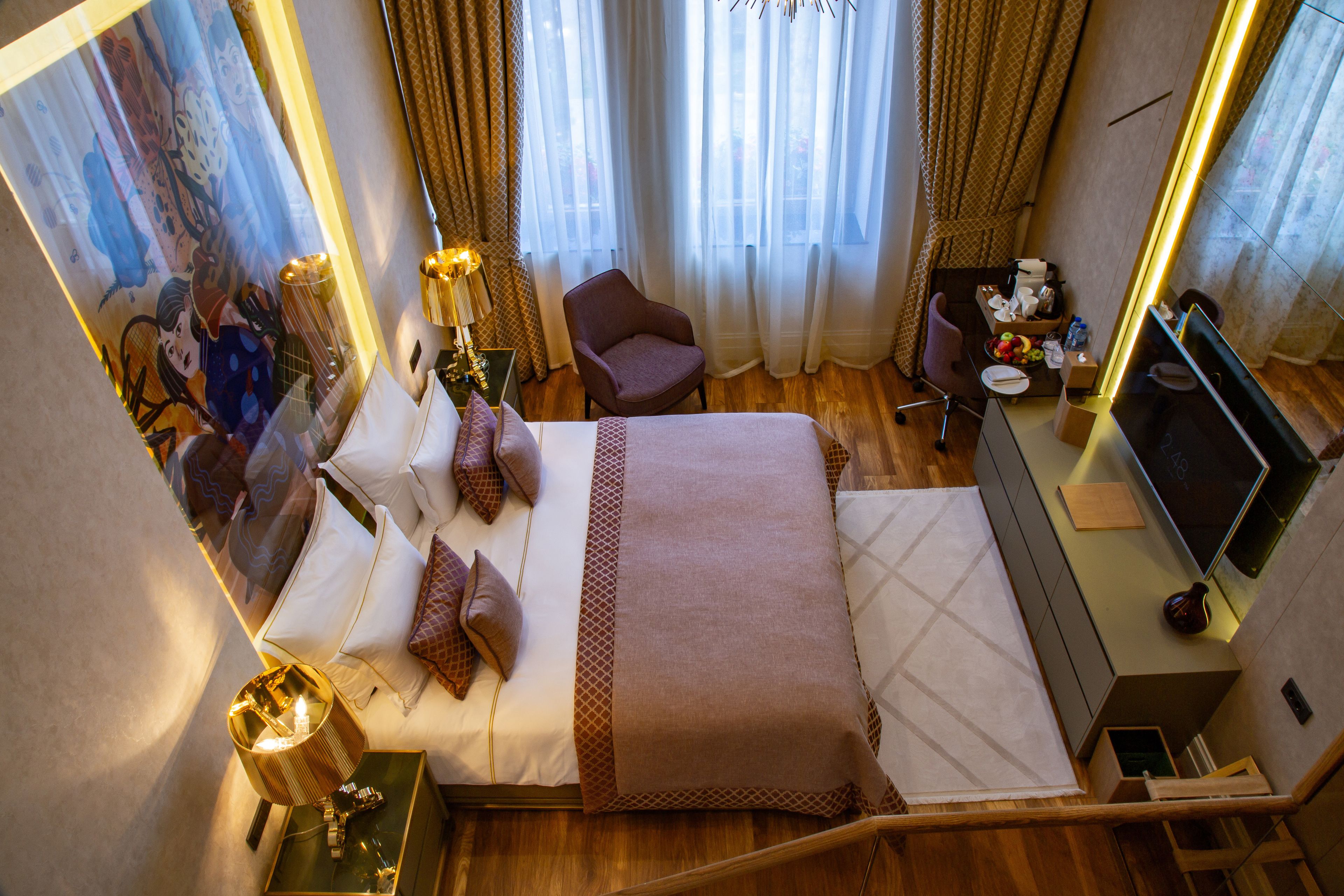 A hotel room with a bed, a desk, a chair, a television, and a window with curtains.