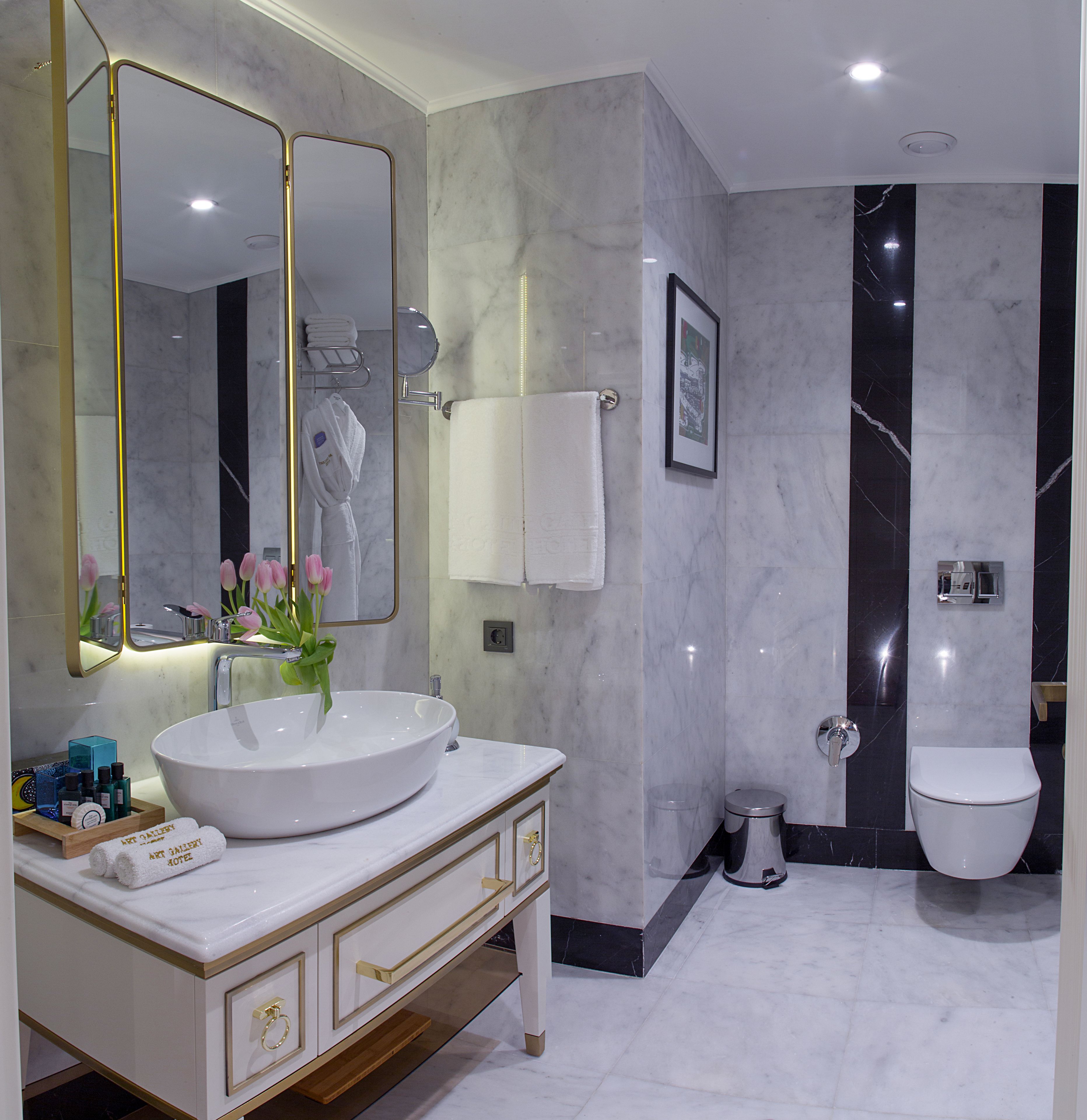A modern bathroom with a large white sink, a mirror, and a toilet.