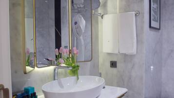A bathroom with a white sink, gold-toned cabinet, and a large mirror with gold trim.