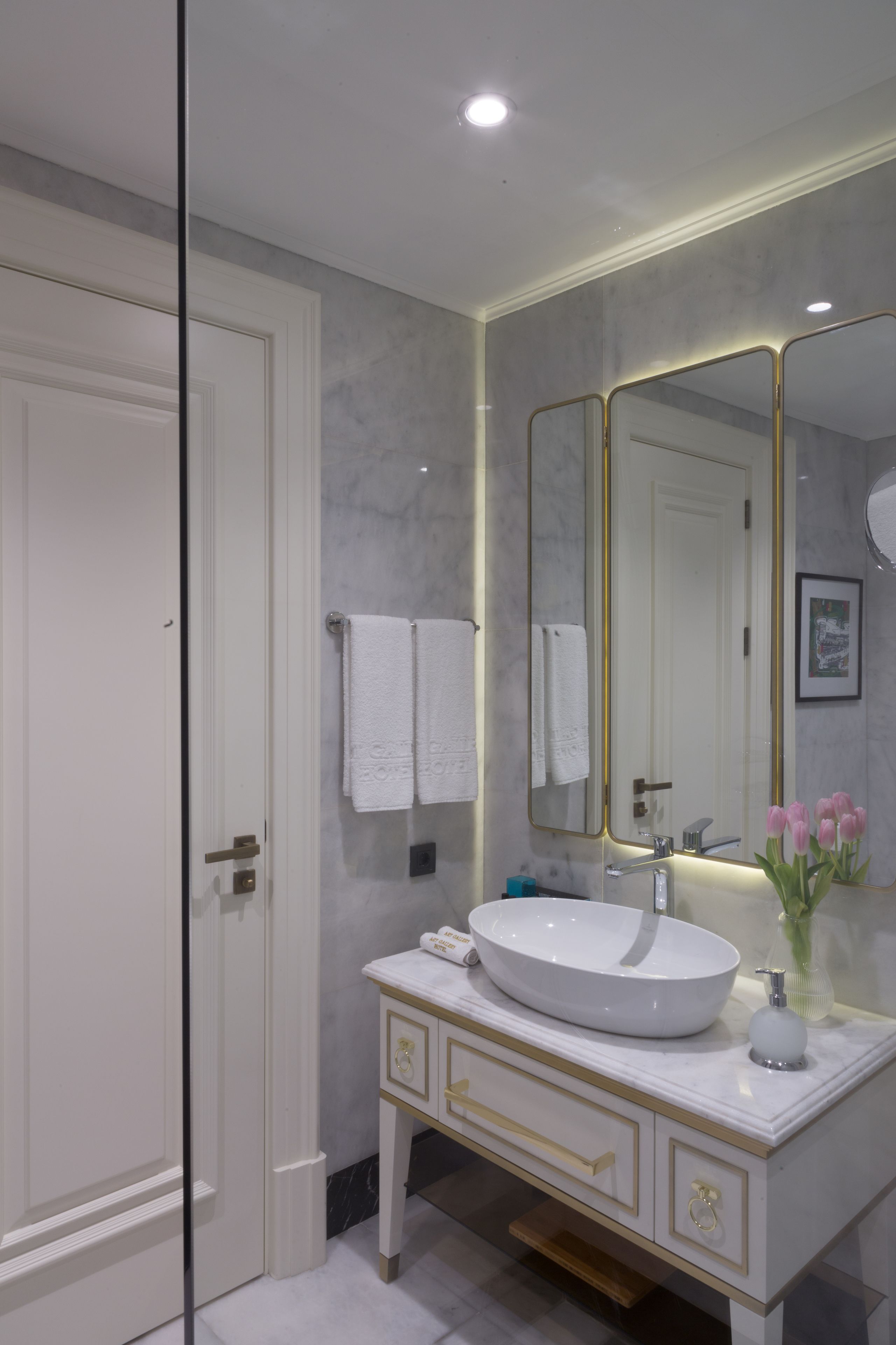 A modern bathroom with a white vanity, a large mirror, and a white sink.