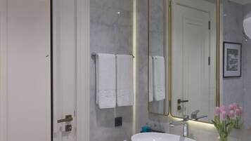 A modern bathroom with a white vanity, a large mirror, and a white sink.