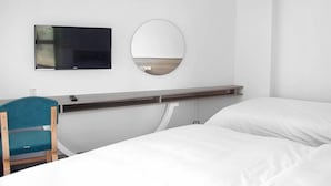 A hotel room with a bed, a desk with a chair, a TV, and a mirror. - Assos Altin Hotel (Ayvacik)