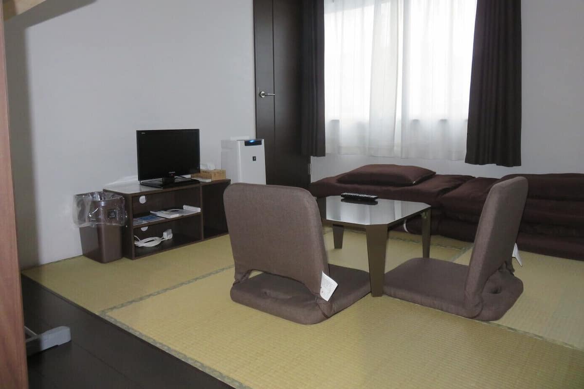 Una sala de estar con televisor, sofá y dos sillones.