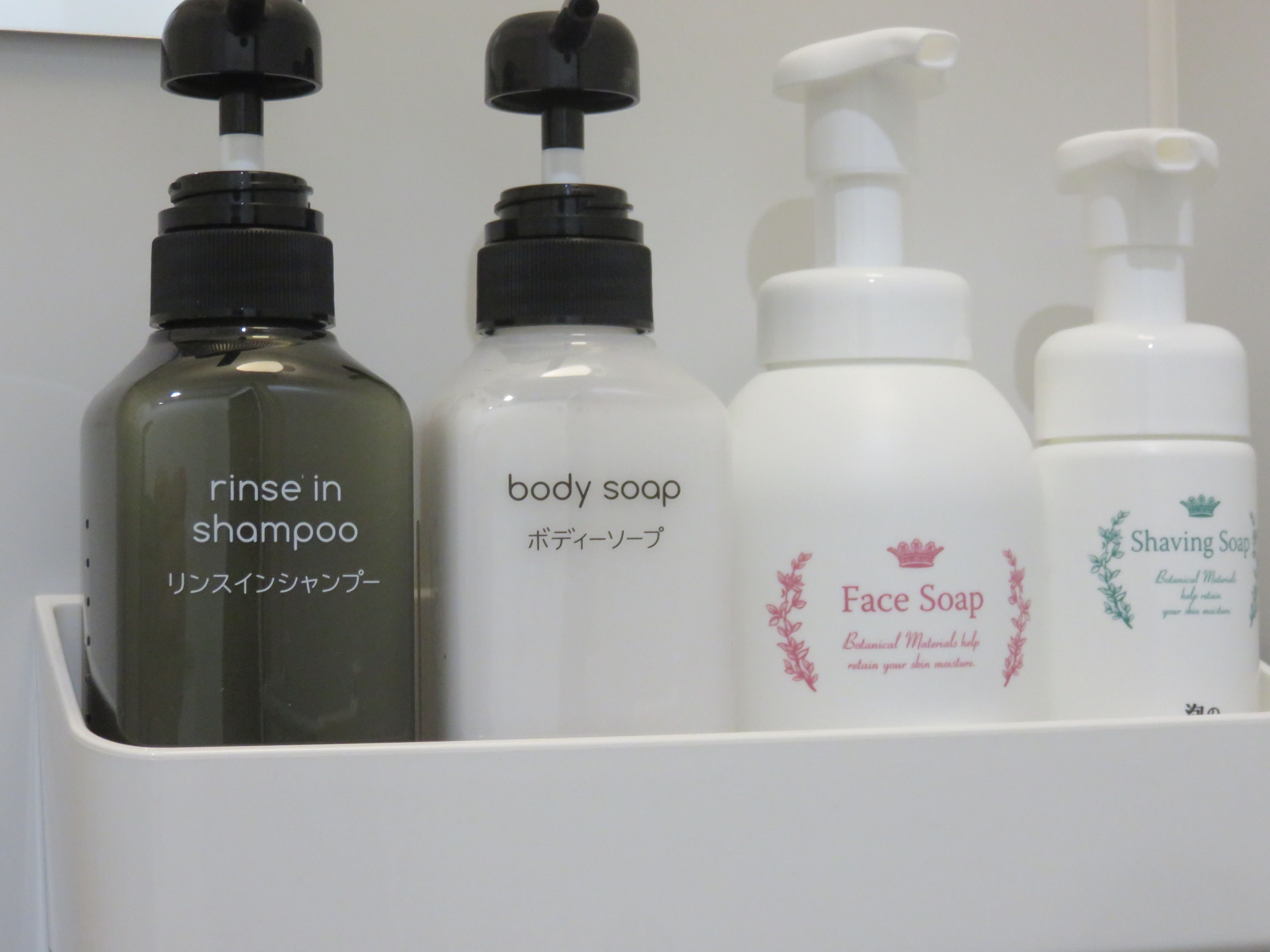 A set of four bottles of personal care products in a white container.