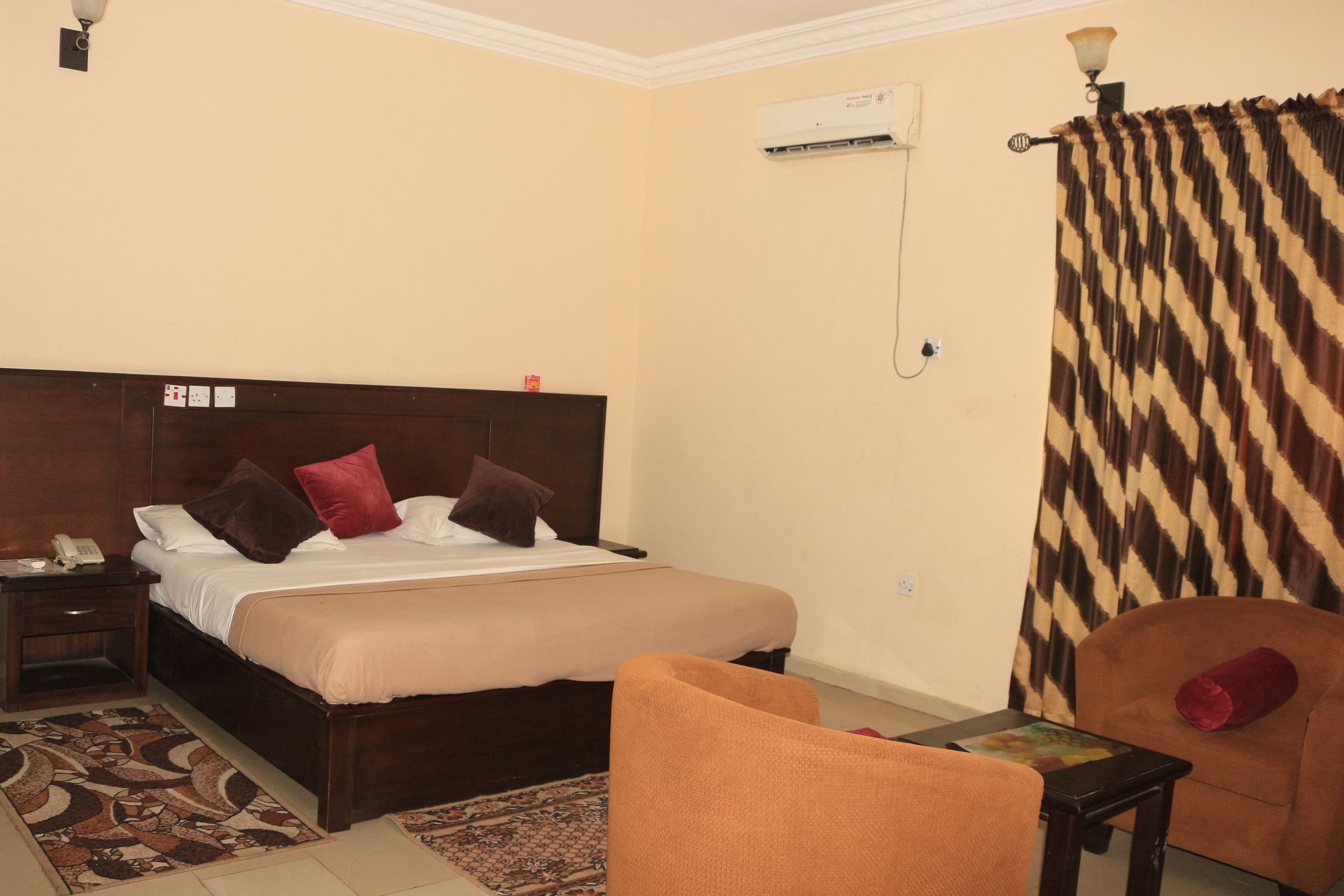 A bedroom with a bed, nightstand, chair, and a table with a book.