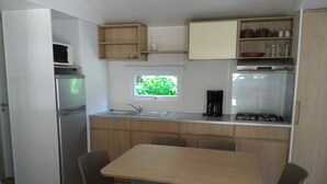 Cocina compacta con refrigerador, pileta, estufa y ventana que proporciona luz natural.