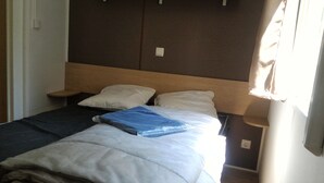 Una cama con cabecera de madera, dos almohadas y una manta azul.