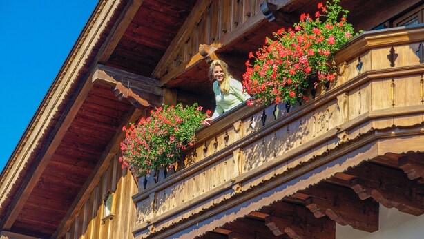 Ein aus Holz erstellter Balkon mit aufwendiger Geländerarbeiten und Blumenkästen.