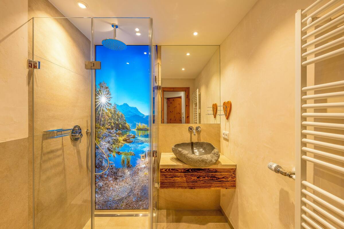 A modern bathroom with a glass-enclosed shower, a wooden vanity, and a large mirror.