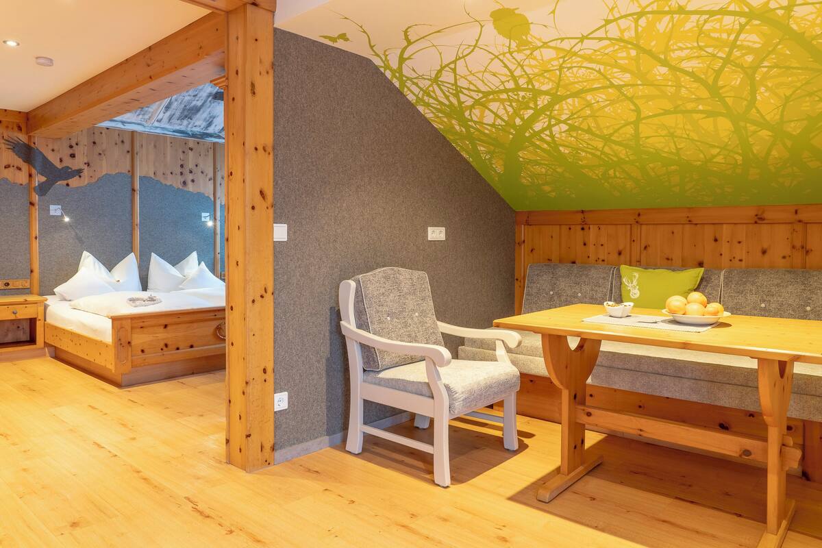 A cozy room with a bed, a chair, and a table with a bowl of fruit.