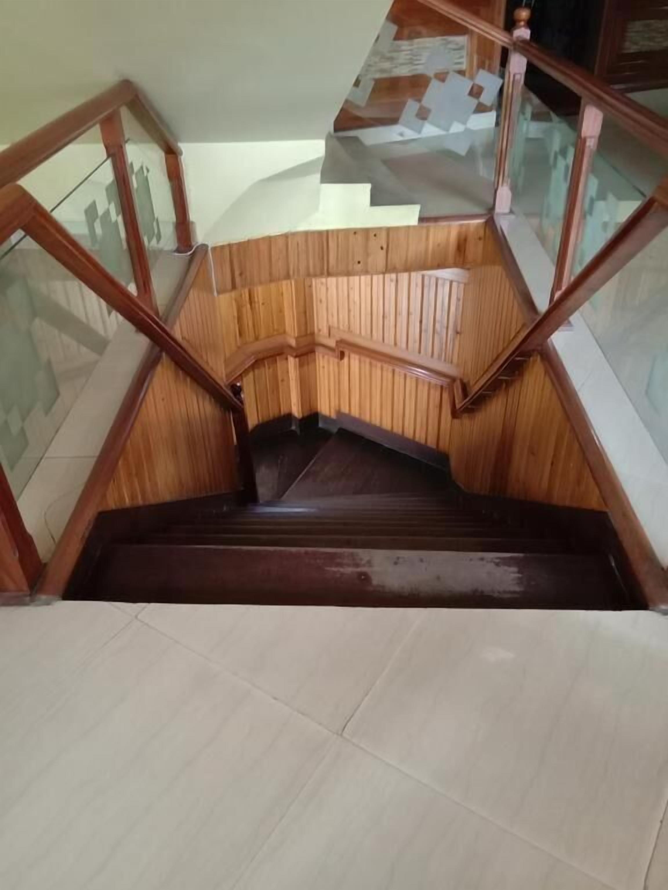 A wooden staircase with glass railings and a tiled floor.