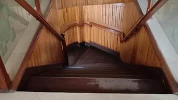 A wooden staircase with glass railings and a tiled floor.
