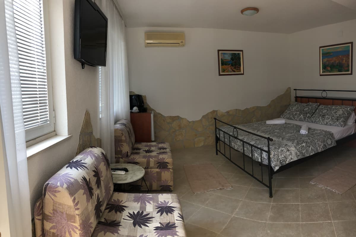 Quarto com cama, sofá, uma mesinha e duas pinturas na parede.