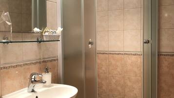 Un baño con ducha envuelta en vidrio, un lavabo con espejo y un borde decorativo de azulejos.