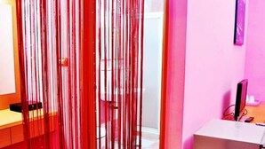 A room with a desk, a chair, a television, and a curtain with vertical stripes. - See Starsea Guest House (Magong)