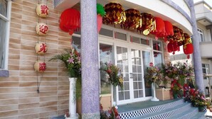 A building facade with a tiled entrance, a decorative column, and a series of hanging ornaments. - See Starsea Guest House (Magong)
