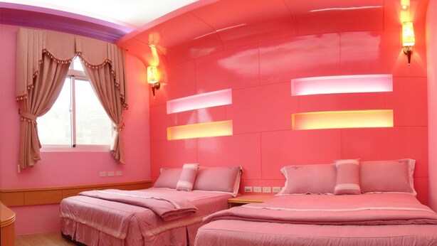 A pink-themed bedroom with two beds, a window with curtains, and wall-mounted lights. - See Starsea Guest House (Magong)