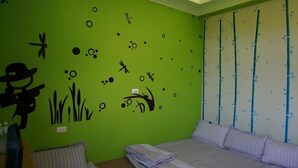 A room with a green wall, a bed with striped bedding, a pillow, and a small table with a chair. - See Starsea Guest House (Magong)