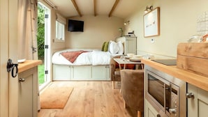 Ein kleines Schlafzimmer mit einem Bett, einem Tisch, einer Mikrowelle und einem Fenster.