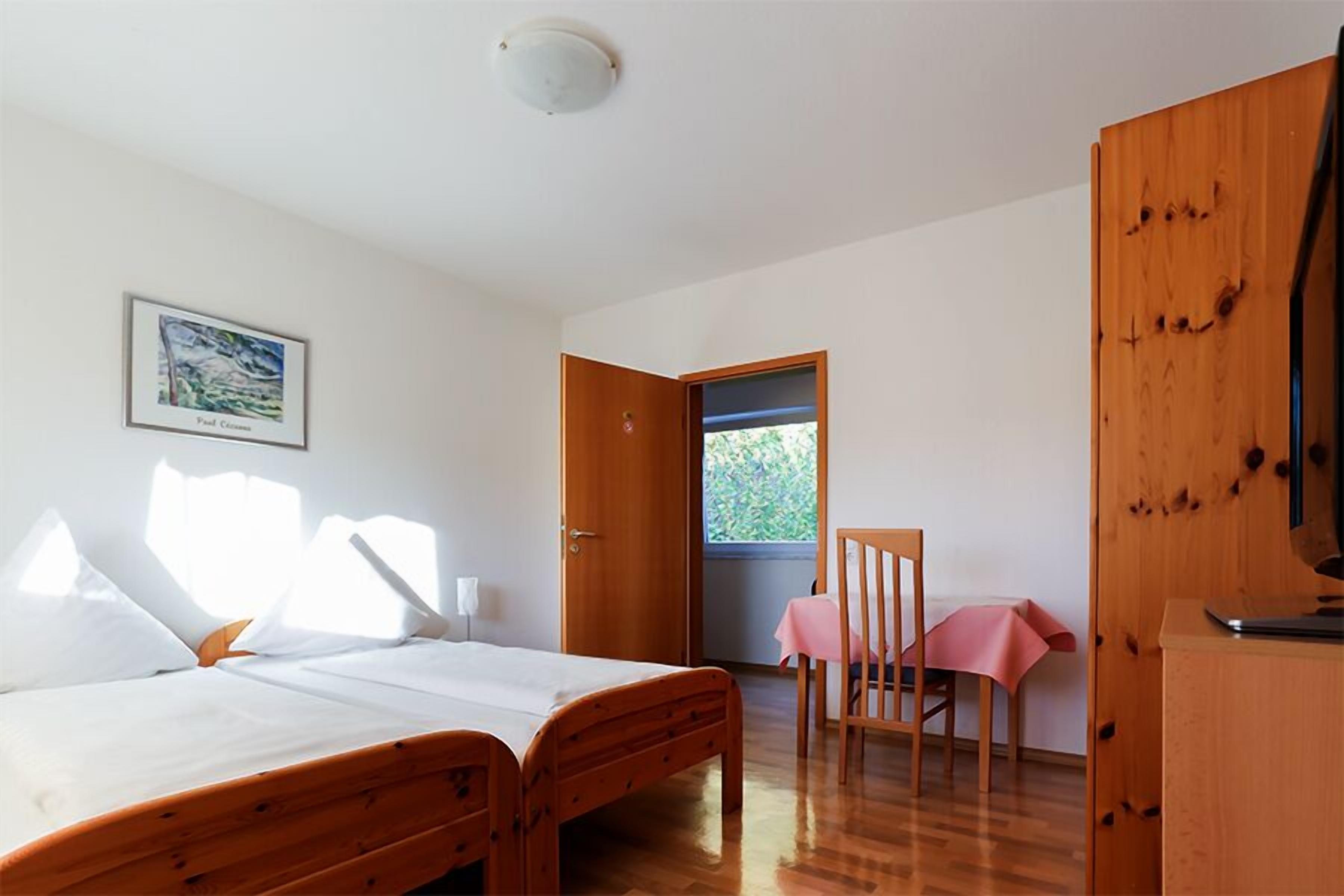 A bedroom with a bed, a chair, a table, and a wardrobe.