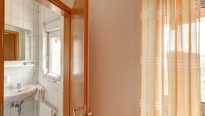 Un baño con lavamanos, espejo y ventana con cortinas.