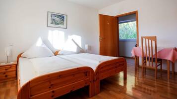 Un dormitorio con una cama de madera, un escritorio con silla, una ventana y una puerta.