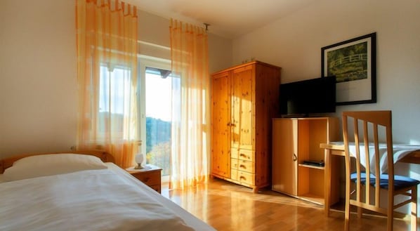 A bedroom with a bed, wooden wardrobe, a desk, and a chair. - Haus Schippke (Otterberg)