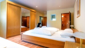 Habitación de hotel con una cama grande, armario de madera y un espejo.