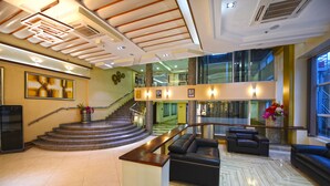 A spacious lobby with a staircase, seating area, and a large window. - BMK House Apartments (Kampala)