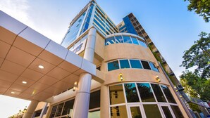 A modern building with a prominent glass facade, large windows, and a covered entrance area. - BMK House Apartments (Kampala)