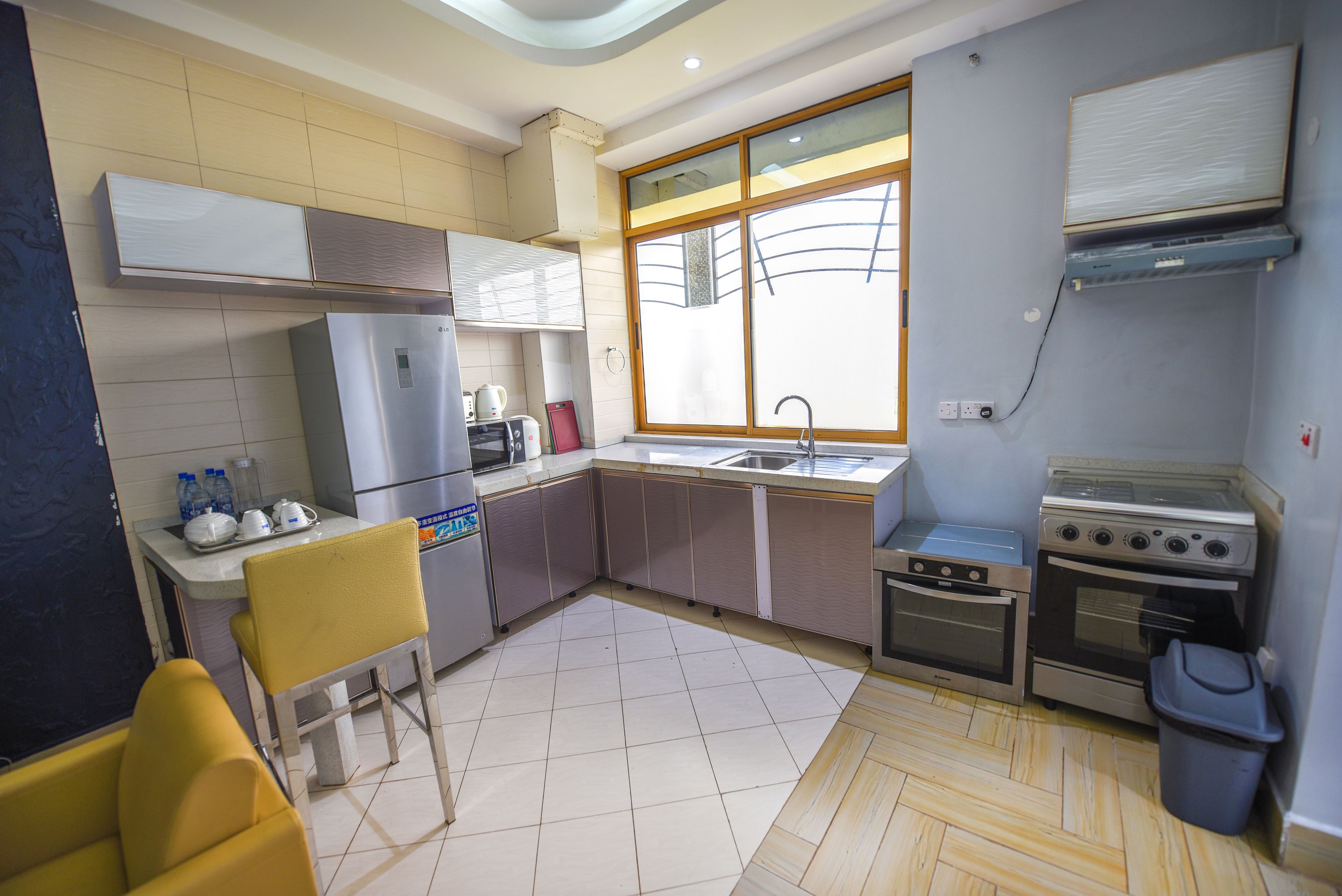 Una cocina compacta con refrigerador, estufa, lavamanos y ventana que proporciona luz natural.