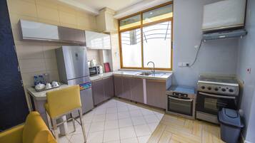 Una cocina compacta con refrigerador, estufa, lavamanos y ventana que proporciona luz natural.