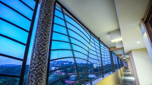A corridor with a view of a cityscape through a window with a metal grid. - BMK House Apartments (Kampala)