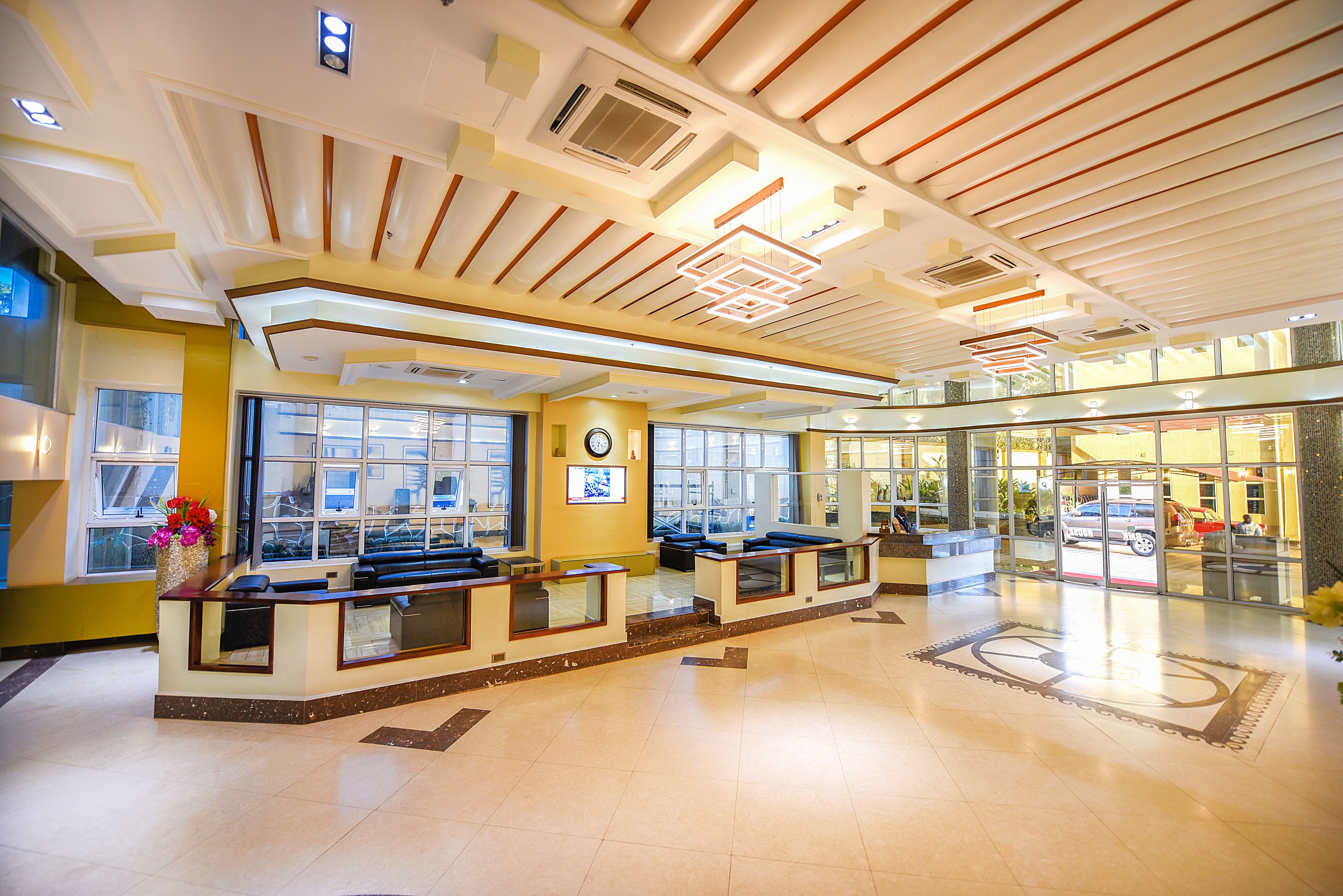 Eine geräumige Lobby mit Empfangsschalter, Sitzgelegenheiten und großen Fenstern mit Blick nach außen.