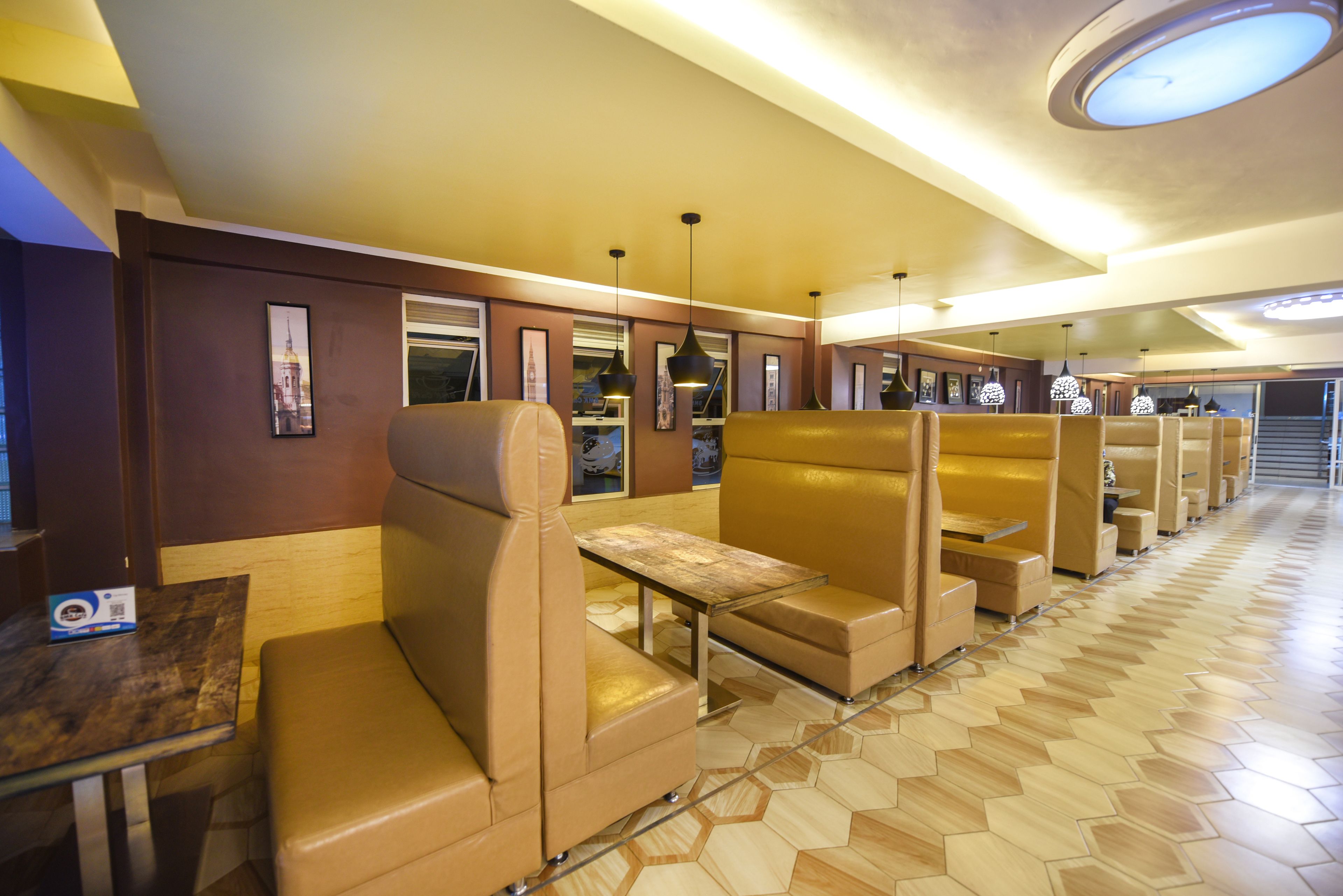 Reihe von Sitzboxen mit einem Holztisch in der Mitte, einem gemusterten Boden und gerahmten Bildern an den Wänden.