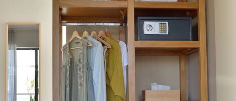 A hotel room with a wooden wardrobe, a bed, and a small refrigerator.
