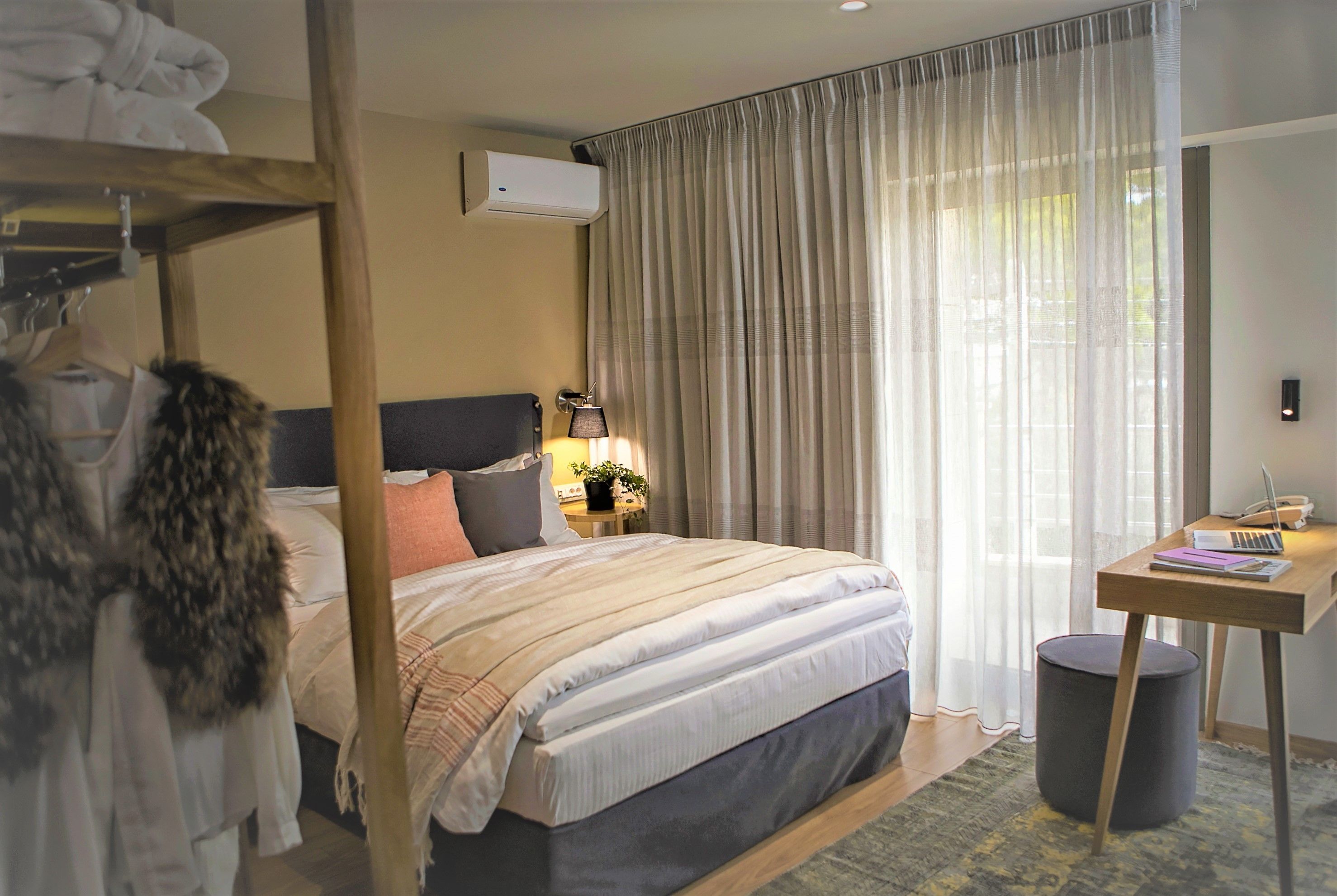 A hotel room with a bunk bed, a desk with a laptop, a lamp, and a small potted plant.