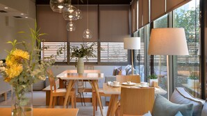 Een moderne eetruimte met een tafel, stoelen, een vaas met bloemen en een bank met kussens.